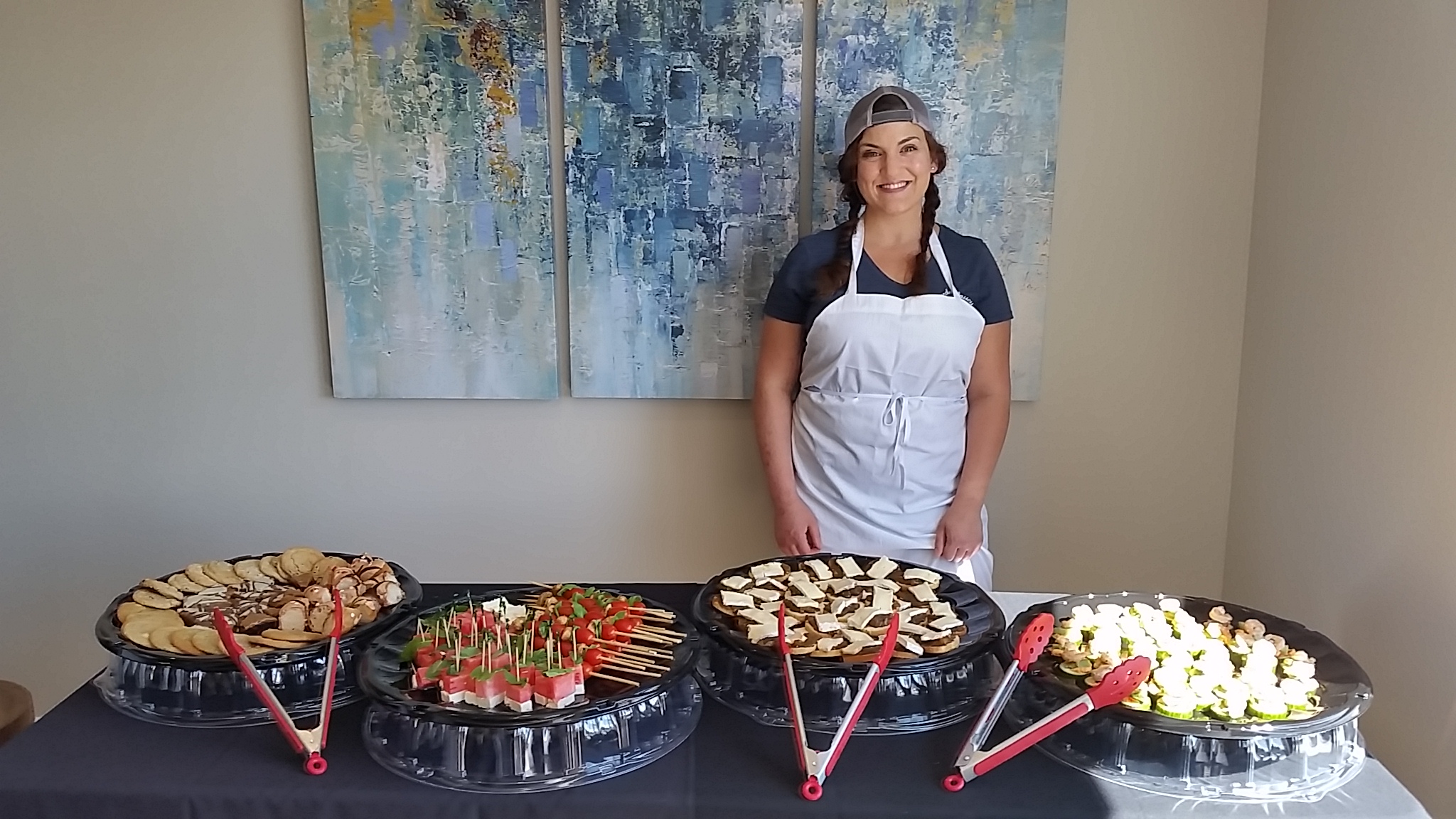 Ellise in front of abstract paintings and behind her food catering service