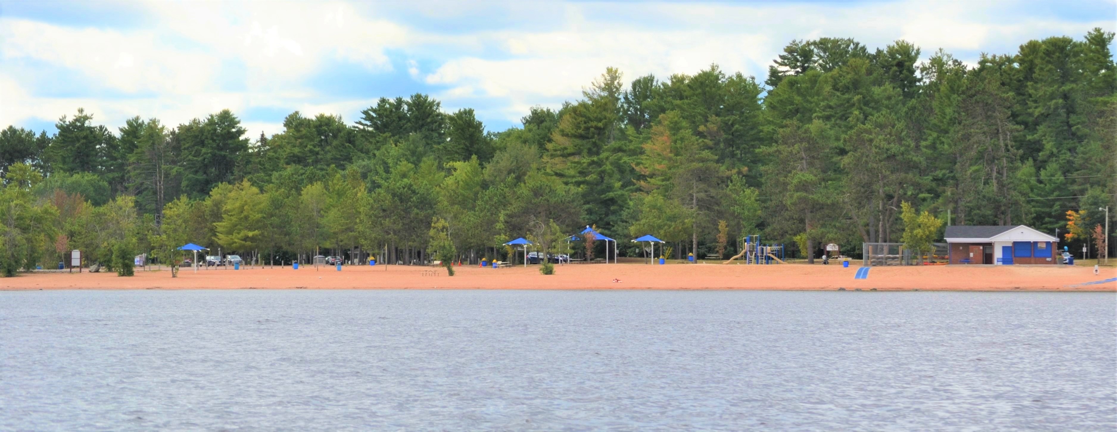 photo from water of wide beach, play structure, trees