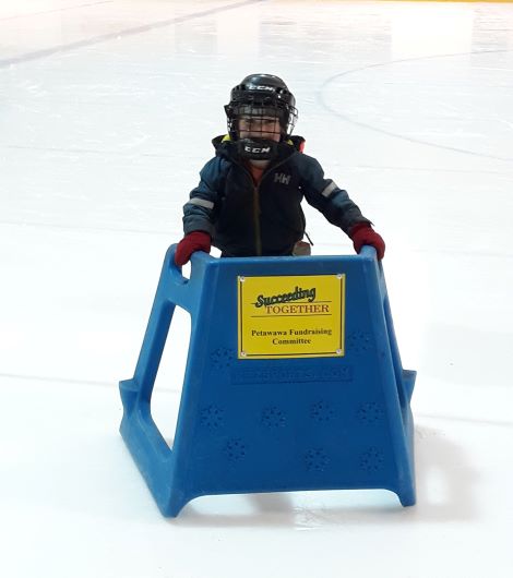 Photo of small child using plastic skating aid on the ice