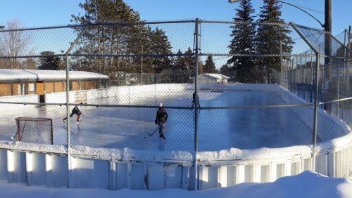 Photo of outdoor rink on a sunny day with 3 skaters