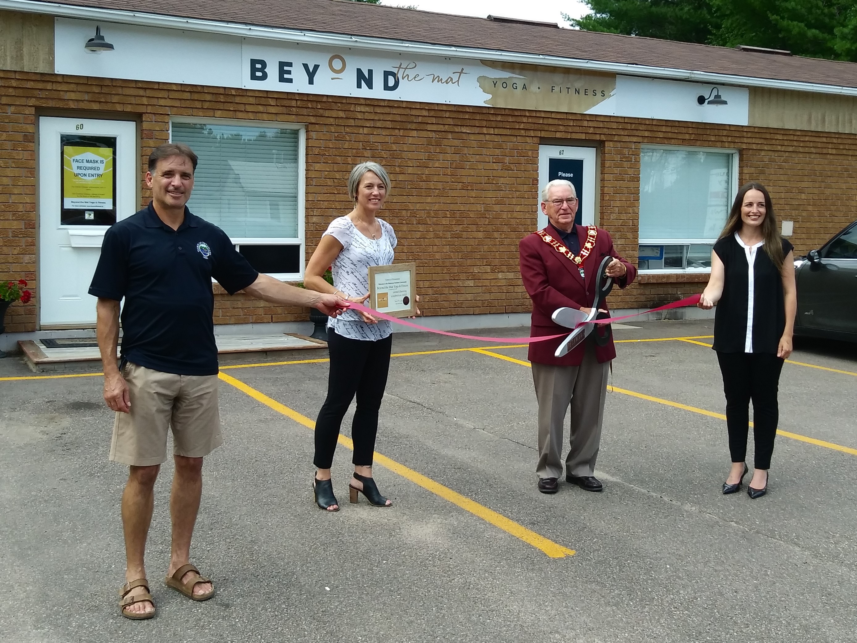 an exterior image of a building with four people holding ribbon and on with giant scissors