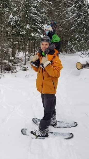 Image of father and toddler snowshoeing in a winter forest scene